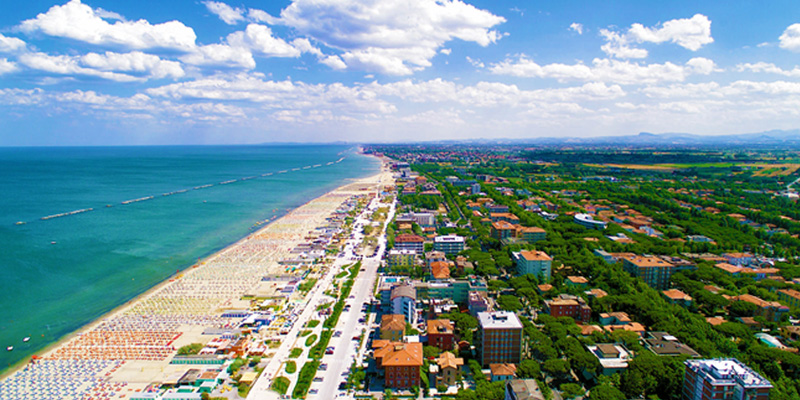 Vista dall'alto su Cesenatico. La psiaggia di sabbia fine e dorata è circondata da un'entroterra ricco di vegetazione. 