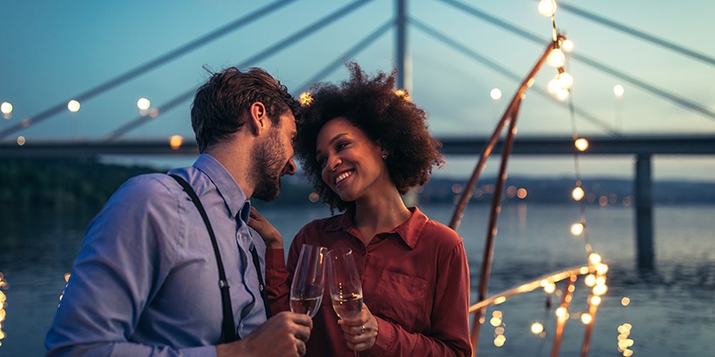 coppia si guarda teneramente negli occhi mentre brinda con un calice di champagne.