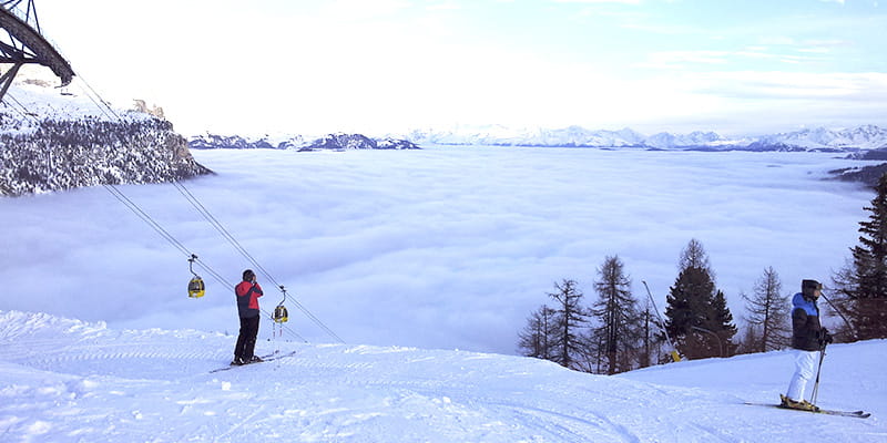 Uno sciatore in piedi su una pista, guarda verso l'orizzonte della vallata innevata dell'Alta Badia.