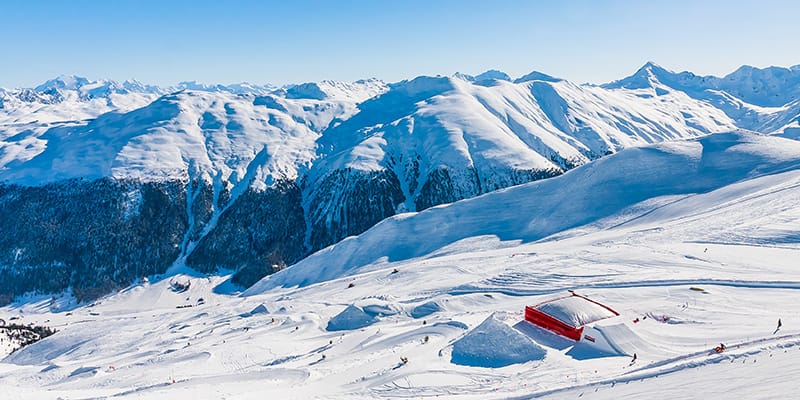 La vallata bianca ricoperta di soffice neve di Livigno si apre contornata dalle cime delle montagne innevate.