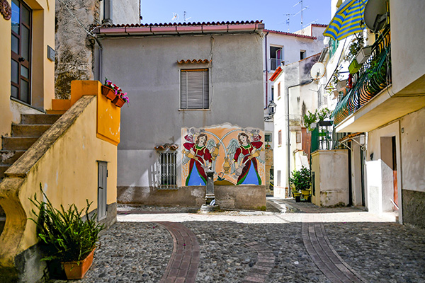 La casette dai toni pastello, la strada di pietra, e i murales colorati sulle facciate delle case rendono unico il borgo di Diamante.